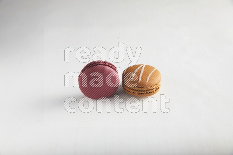 45º Shot of of two assorted Brown Irish Cream, and Red Cherry macarons on white background