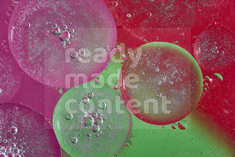 Close-ups of abstract oil bubbles on water surface in shades of pink, green and red