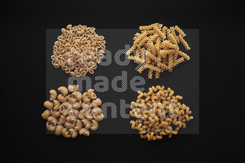 Different pasta types in bunches on black background