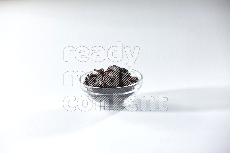 A glass bowl full of dried plums on a white background in different angles