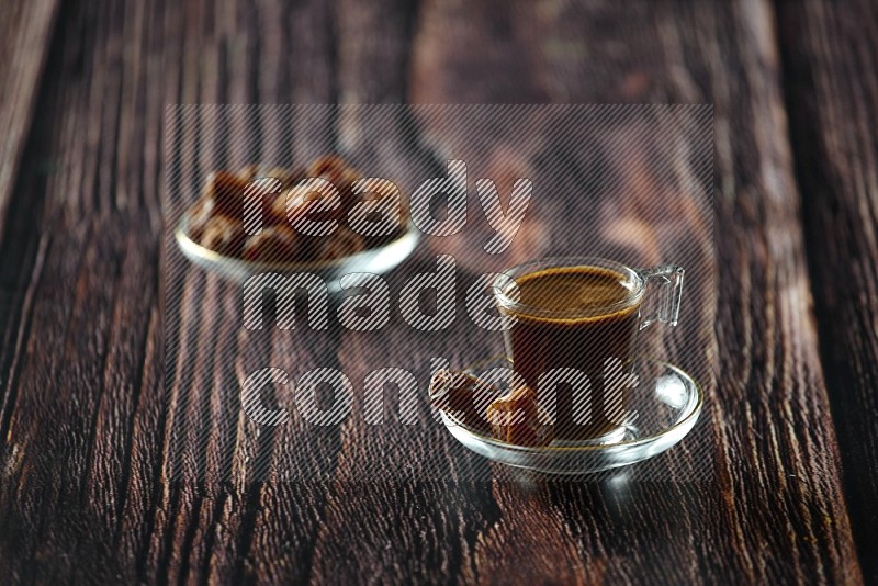 A coffee glass cup with dates and tea on wooden background