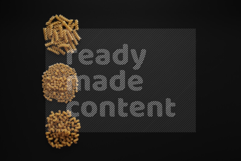 Different pasta types in 3 bunches on black background