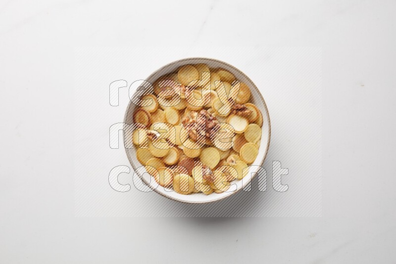 Top-view shot of walnut cereal pancakes in a round bowl on white background