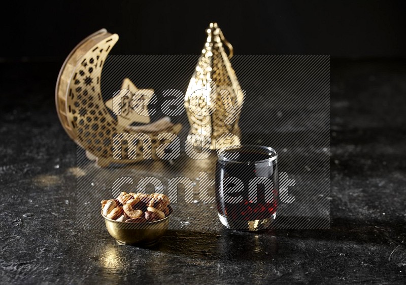 مكسرات في وعاء معدني مع مشروب التمر الهندي بجانب فوانيس ذهبية علي خلفية سوداء