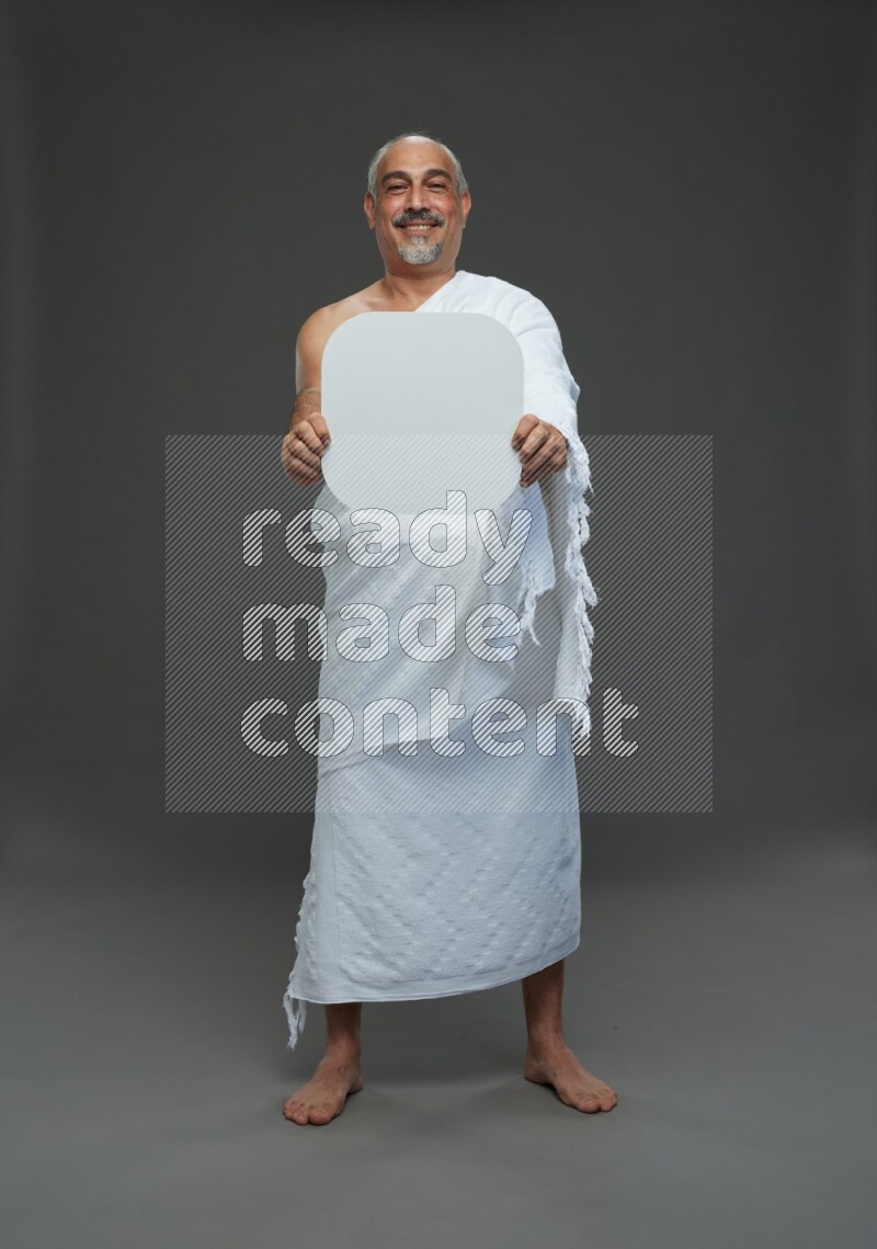 A man wearing Ehram Standing holding social media sign on gray background
