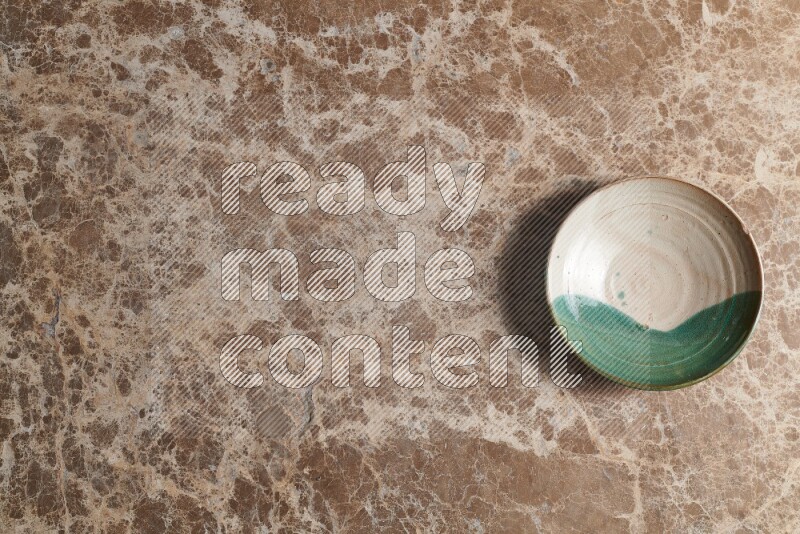 A decorative pottery plate on beige marble background