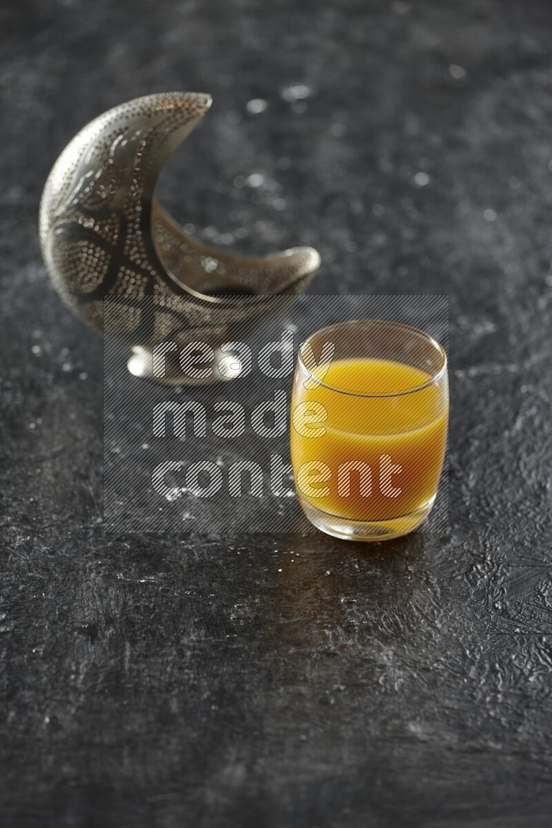 فانوس فضي مع مشروبات مختلفة وتمر ومكسرات وسبحة صلاة وقرآن على خلفية سوداء