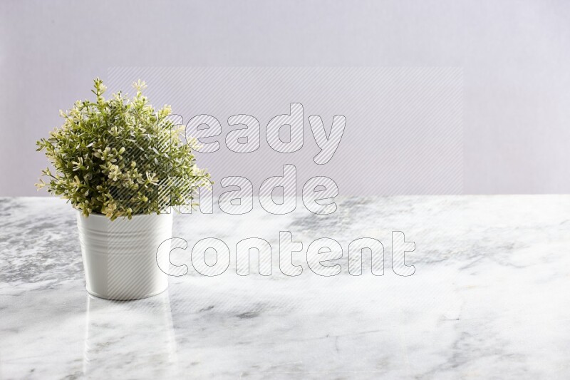 Artificial plant in white pot on grey marble background