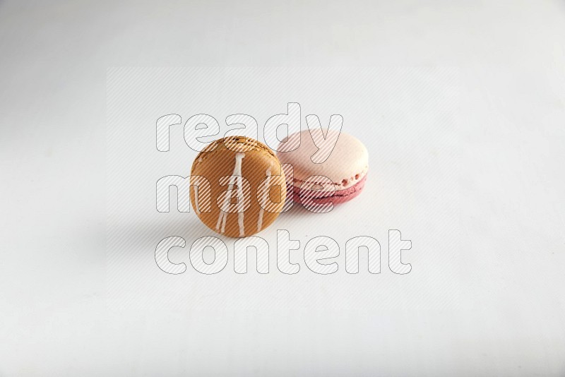 45º Shot of of two assorted Brown Irish Cream, and Pink Litchi Raspberry macarons on white background