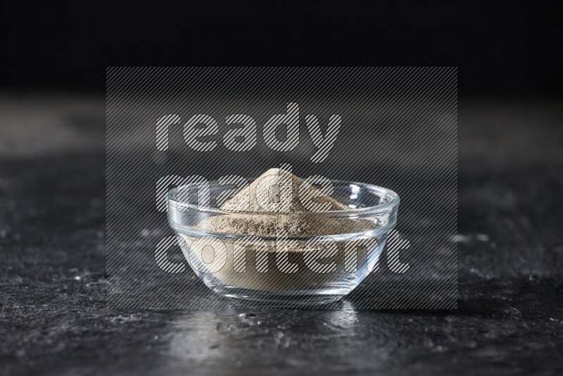 وعاء زجاجي مملوء بمسحوق الفلفل الأبيض على أرضية سوداء