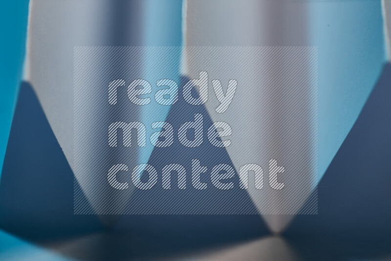 صورة مجردة مقربة تظهر طيات ورقية هندسية حادة بتدرجات اللون الأزرق