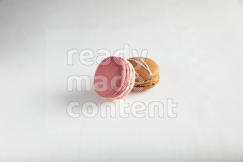 45º Shot of of two assorted Brown Irish Cream, and Pink Litchi Raspberry macarons on white background