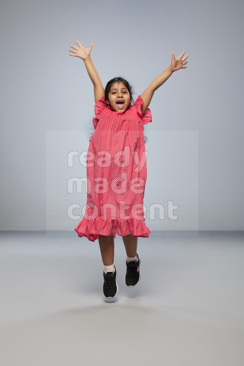 A girl standing interacting with the camera on gray background