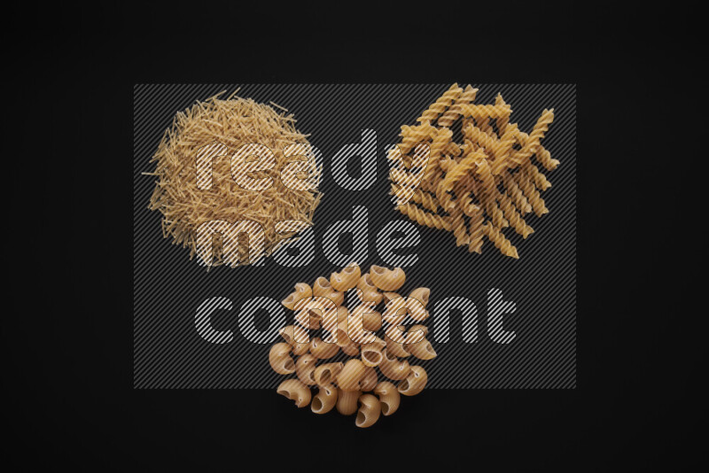 Different pasta types in bunches on black background