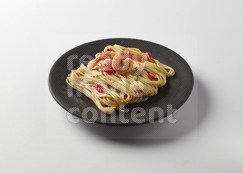 spaghetti pasta with white sauce on a black plate on a white background