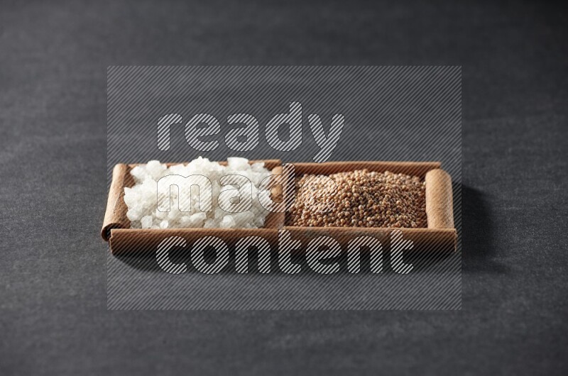 مربعان من أعواد القرفة ممتلئان بحبوب الخردل والملح الأبيض علي خلفية سوداء