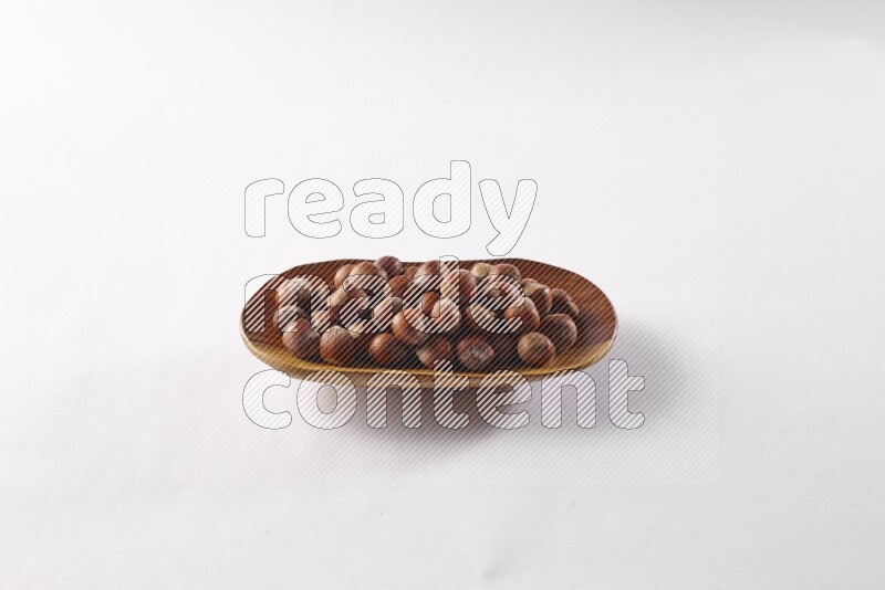 Hazelnuts in a wooden plate on white background