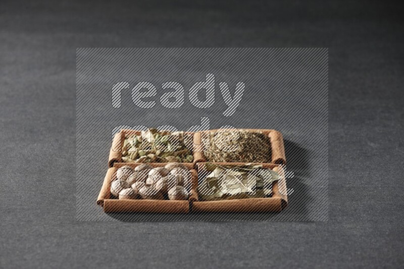 4 squares of cinnamon sticks full of cumin, cardamom, bay laurel leaves and nutmegs on black flooring