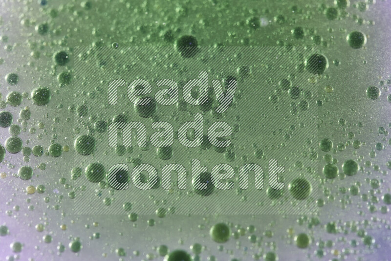 Close-ups of abstract green watercolor drops on oil Surface on white background