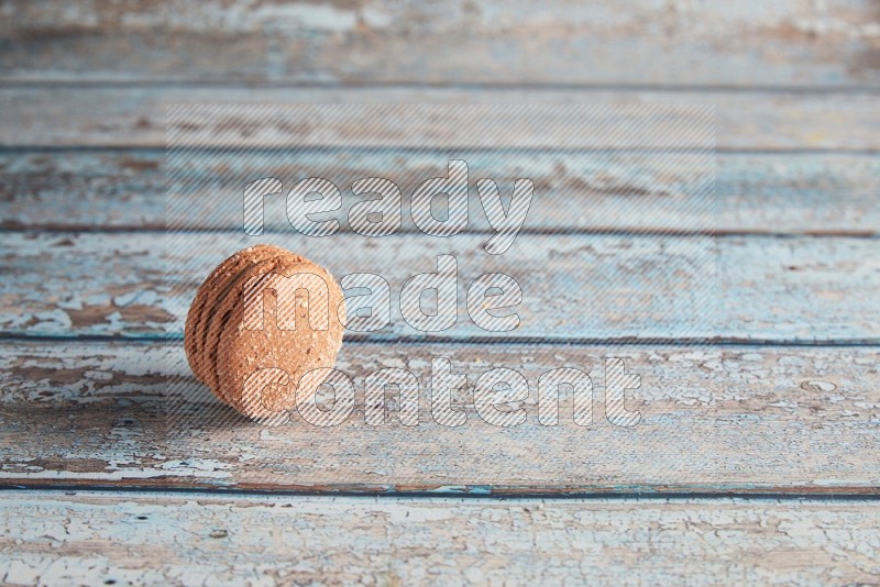 45º Shot of Brown Hazelnuts macaron on light blue wooden background