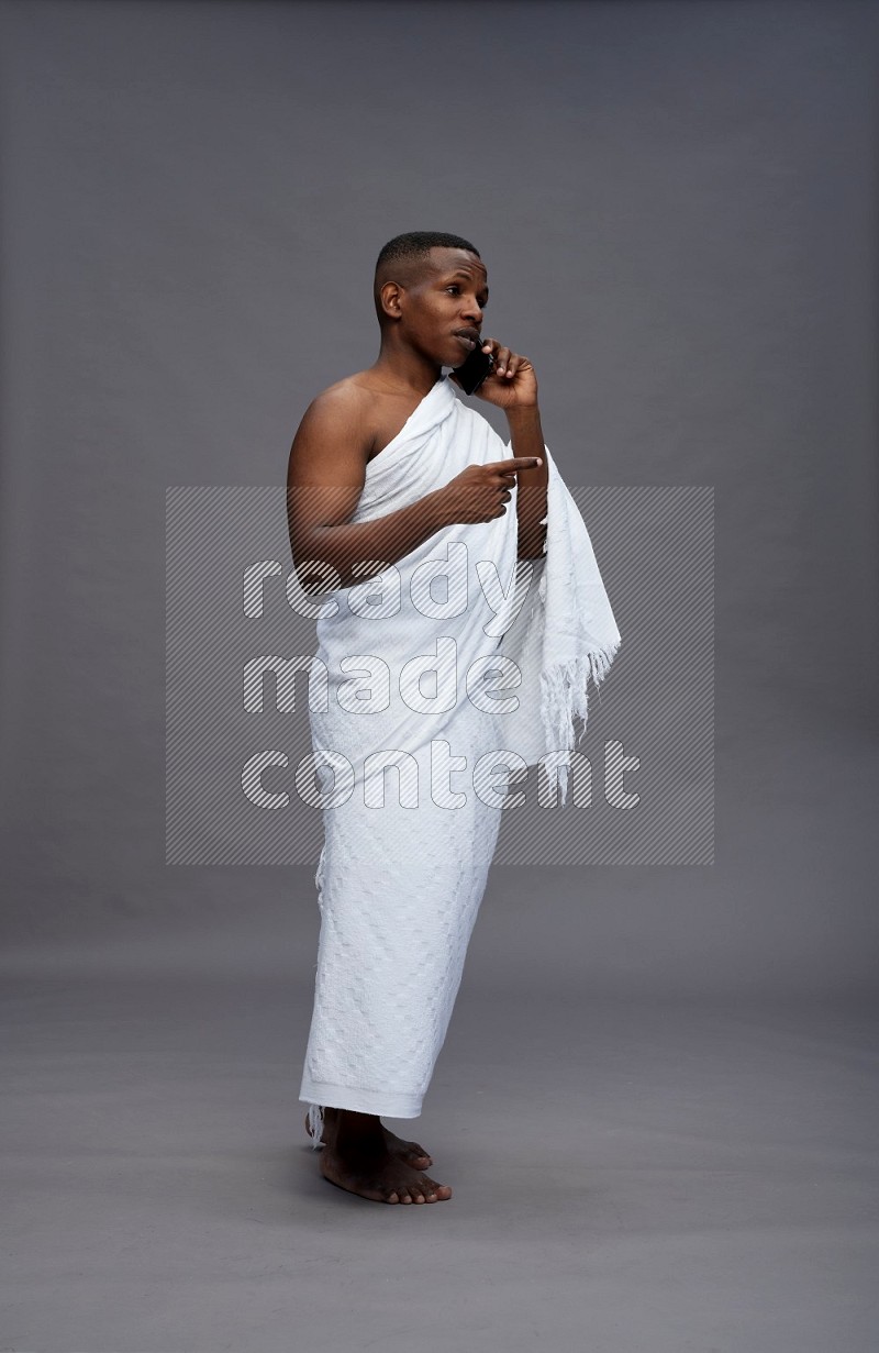 A man wearing Ehram Standing talking on phone on gray background