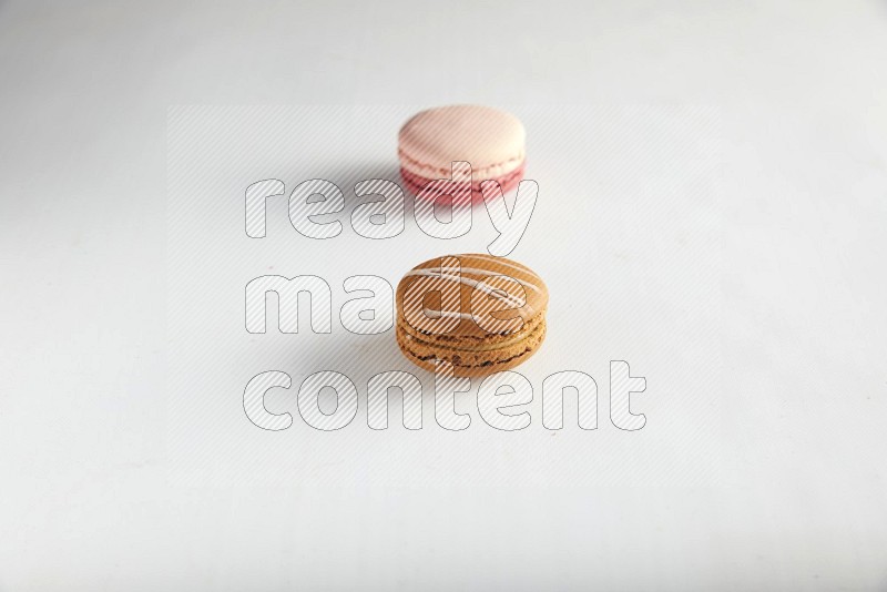 45º Shot of of two assorted Brown Irish Cream, and Pink Litchi Raspberry macarons on white background