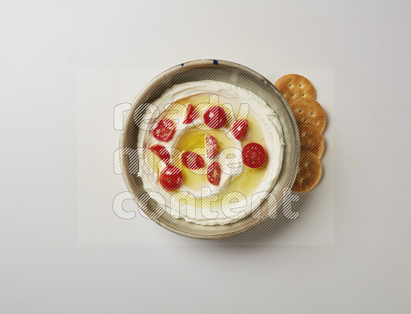 Lebnah garnished with cherry tomato in a grey pottery plate on a white background