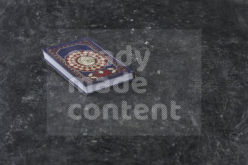 Quran with a prayer beads on textured black background