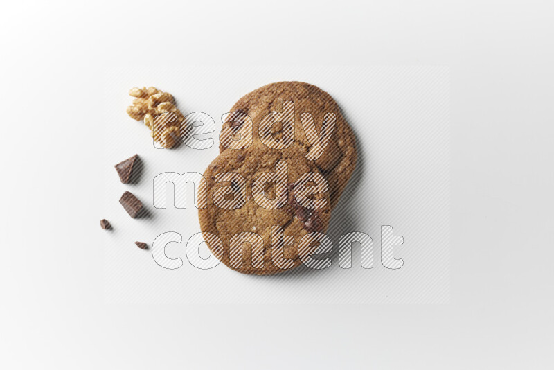 Chocolate chips cookies with chocolate and walnuts beside it on a white background