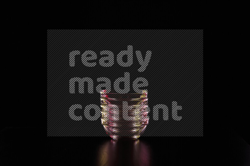 Glassware with rim light in red and yellow against black background