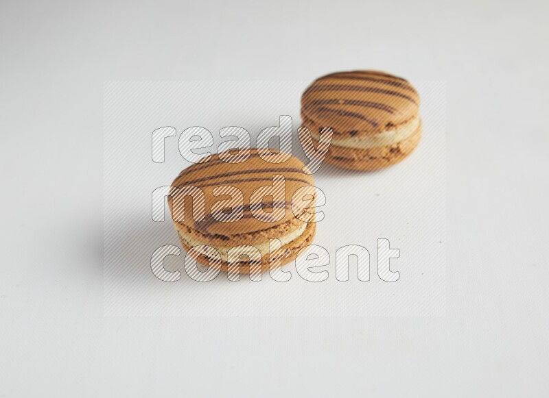 45º Shot of two light brown  Almond Cream macarons on white background