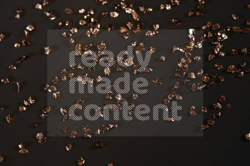 قطع زجاجية برونزية لامعة متناثرة على خلفية سوداء