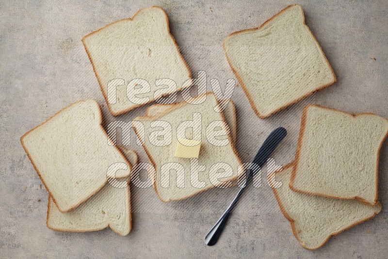 White toast slices with a butter cube and a spreading knife on a light blue textured background