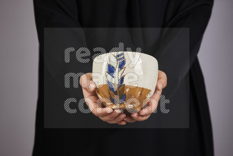 A woman in black abaya holding different pottery essentials in different positions