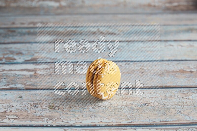 45º Shot of Yellow Piña Colada macaron on light blue wooden background