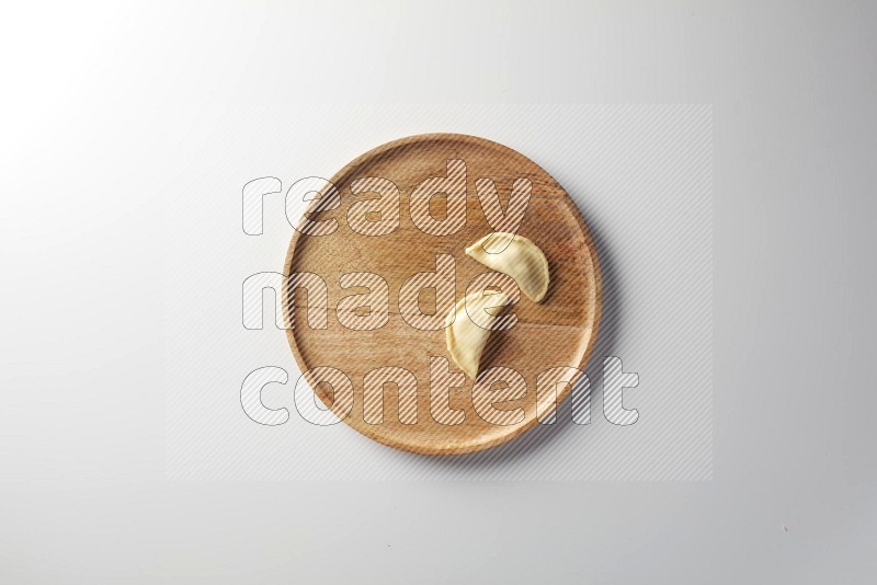 Two Sambosas on a wooden round plate on a white background