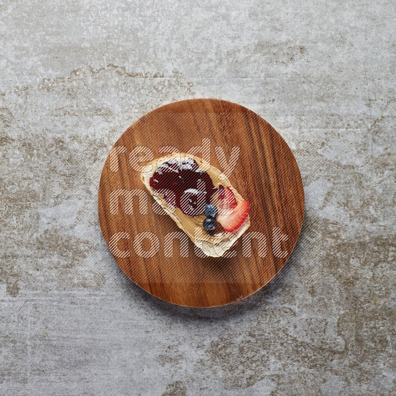 open faced peanut butter sandwich with jam, strawberries and blueberries & chia on a  grey textured background