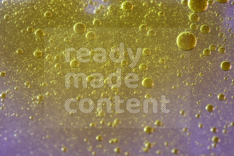 Close-ups of abstract yellow watercolor drops on oil Surface on pink background