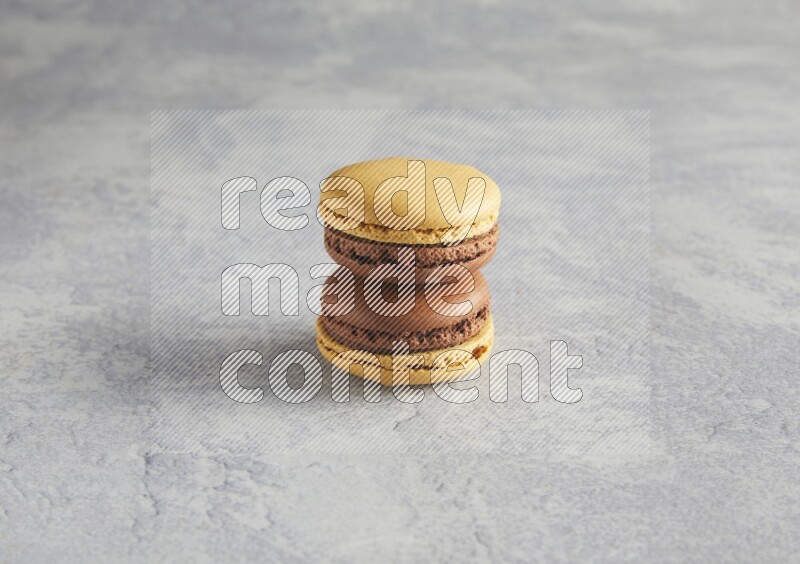 45º Shot of two Yellow and Brown Chai Latte macarons r on white  marble background