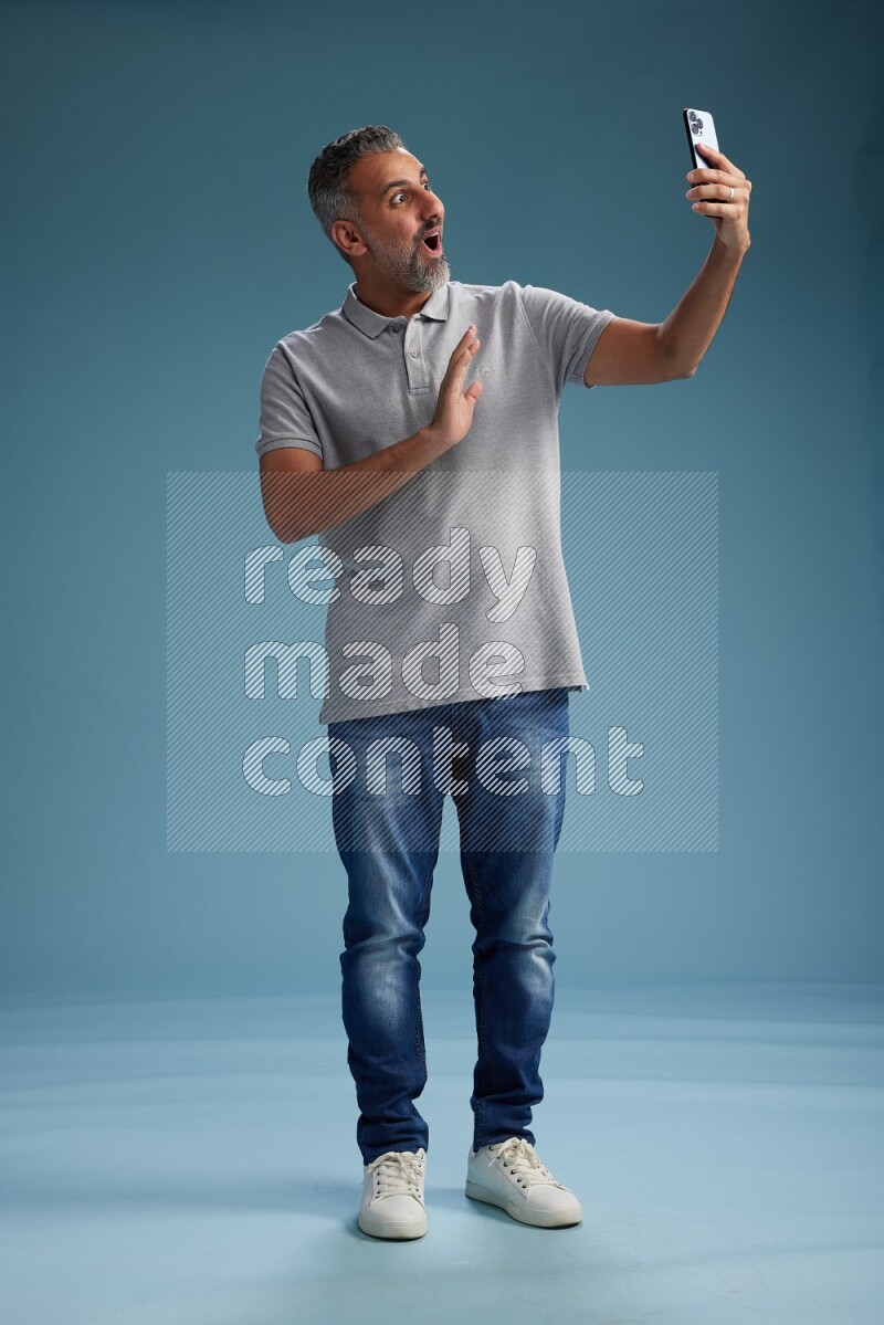 Man Standing taking selfie on blue background