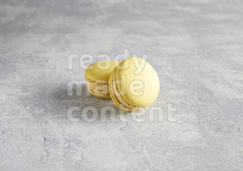 45º Shot of two Yellow Lime macarons  on white  marble background