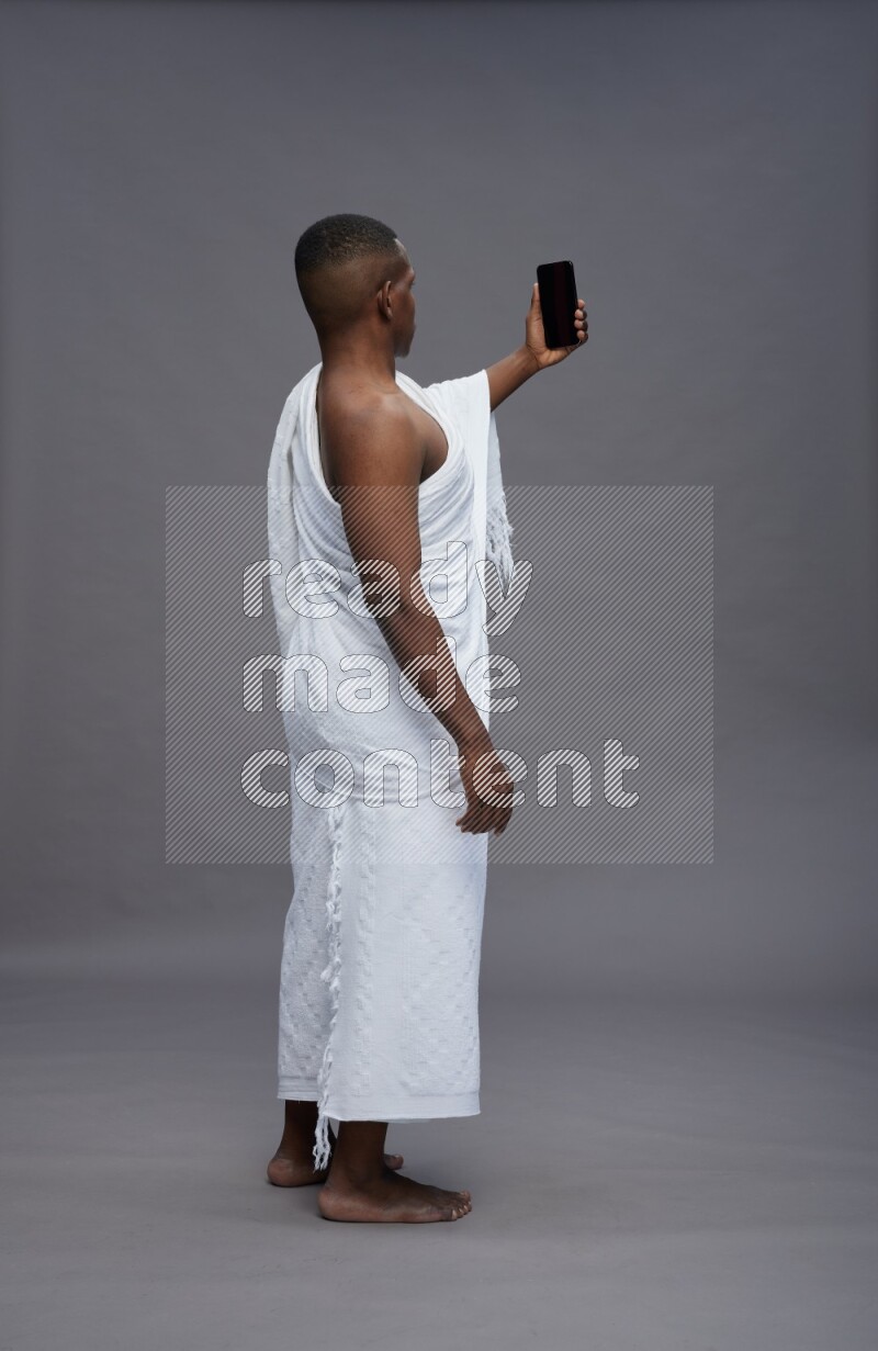 A man wearing Ehram Standing taking selfie on gray background