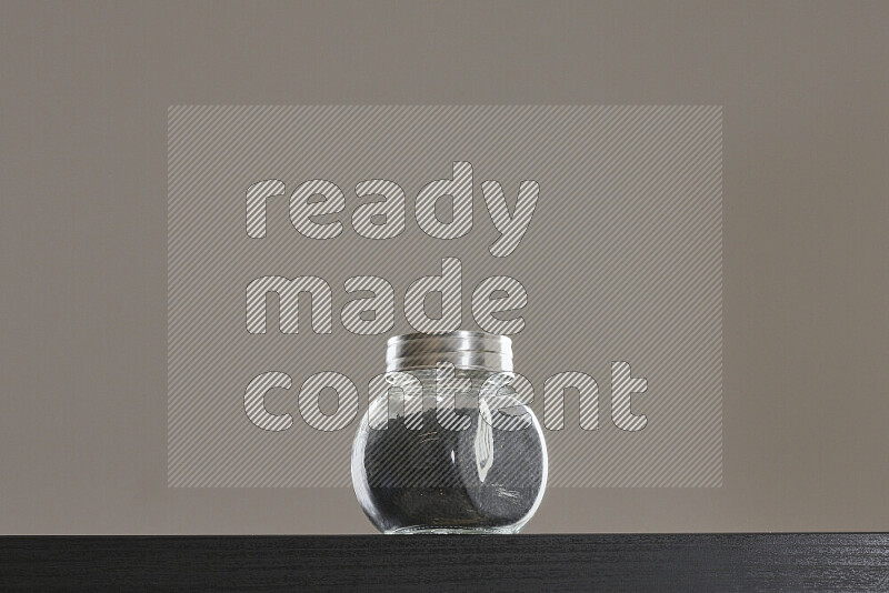 Black seeds in a glass jar on black background