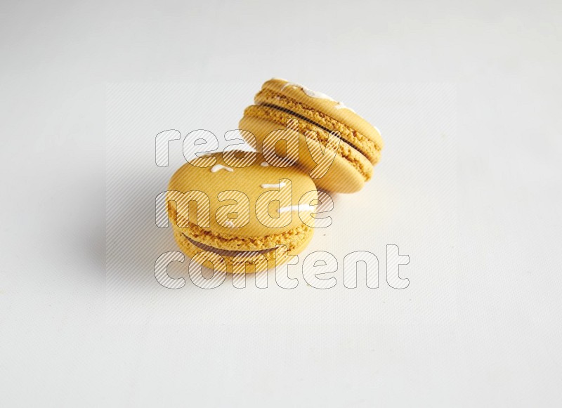 45º Shot of two Yellow Piña Colada macarons on white background