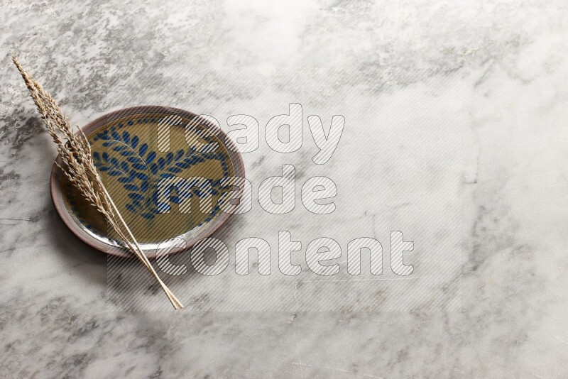 Wheat stalks on decorative pottery plate on grey marble background