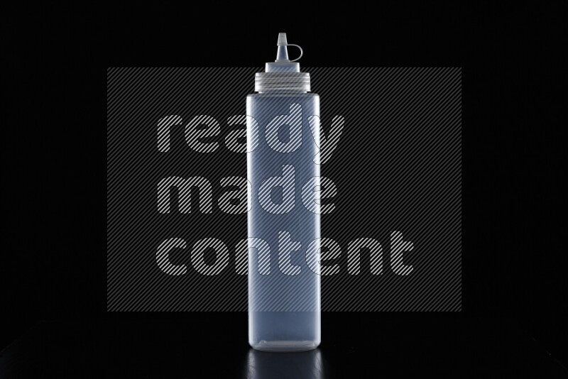 A squeeze bottle with colored rim light against black background