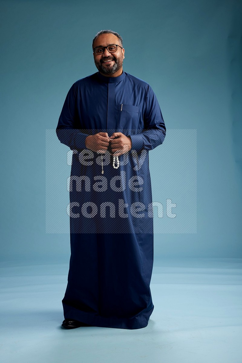 Saudi Man without shimag Standing Interacting with the camera on blue background