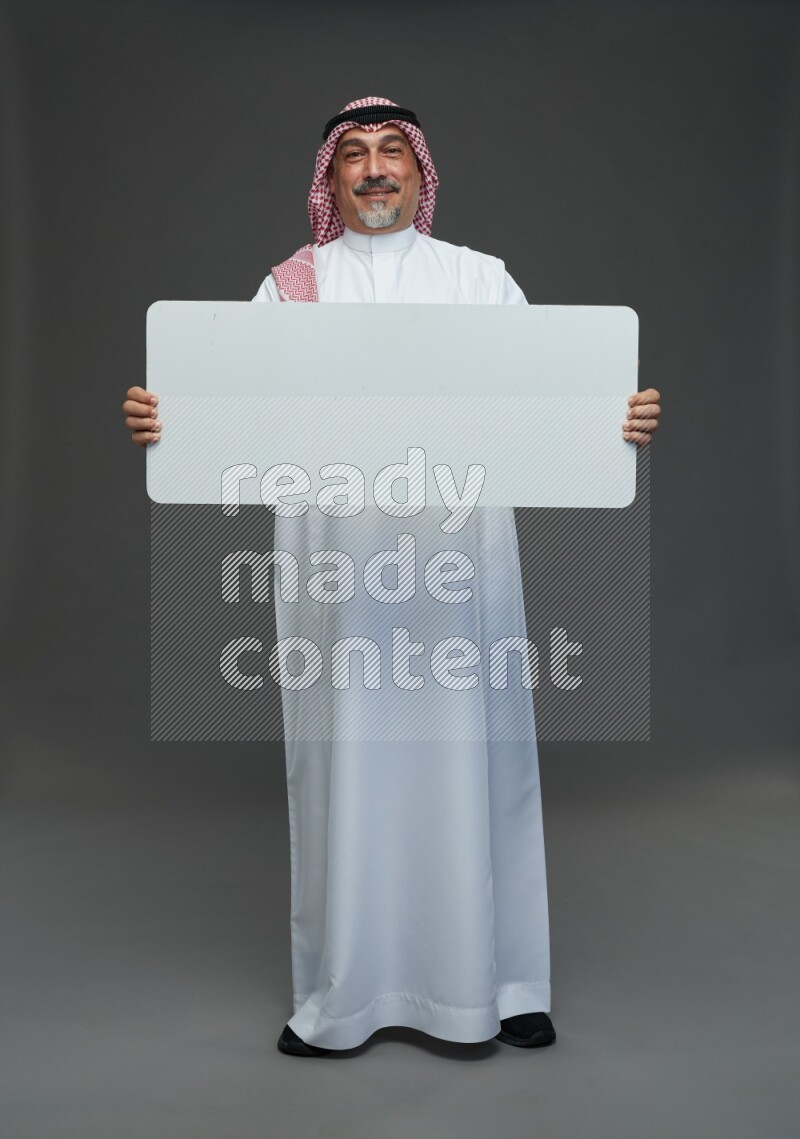 Saudi man with shomag Standing holding social media sing on gray background