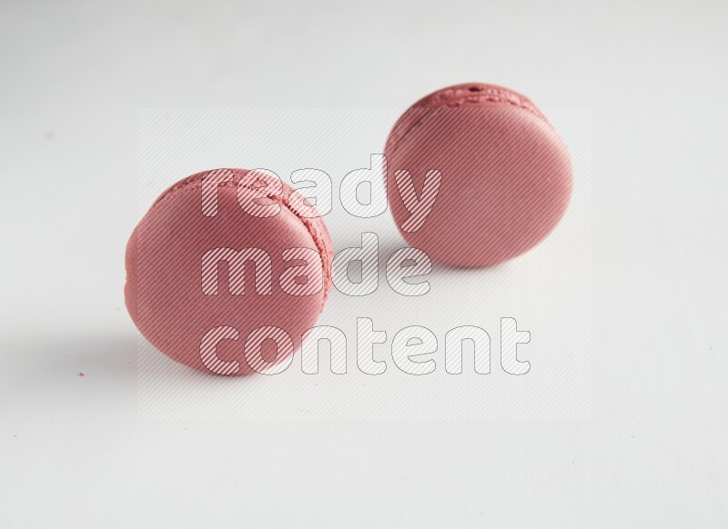 45º Shot of two Pink Raspberry macarons on white background