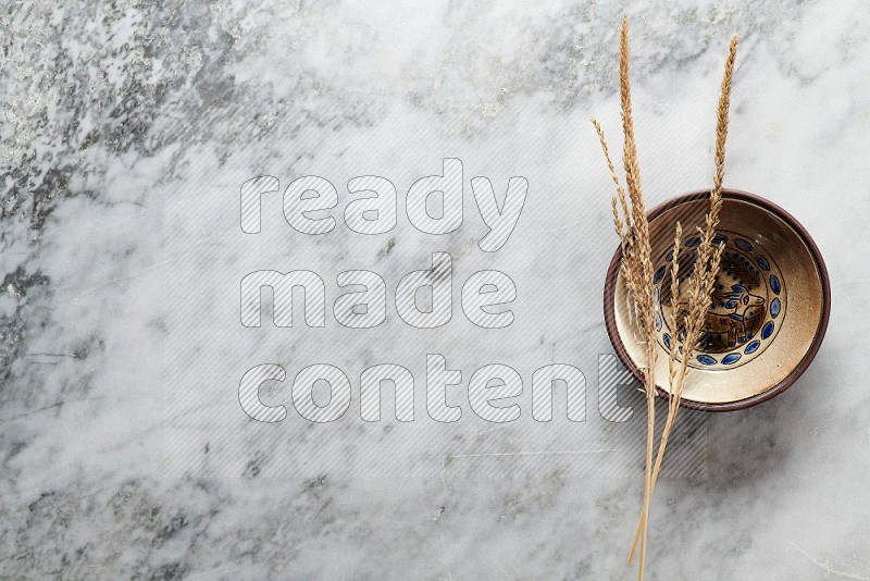 Wheat stalks on Decorative Pottery Plate on grey marble flooring, Top view